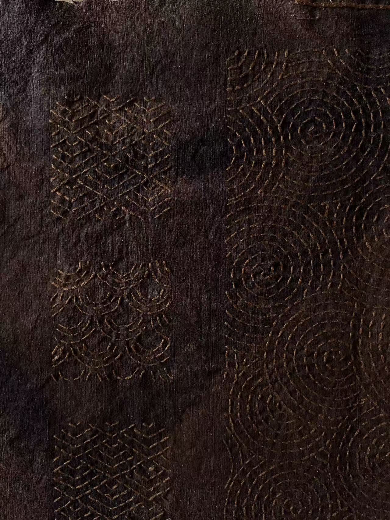 Geometric and circular stitched patterns on a dark textile by Echo Yu